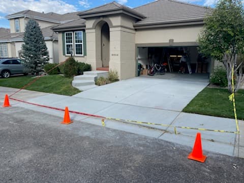 A new concrete driveway in front of a house, taped off with cones while it cures