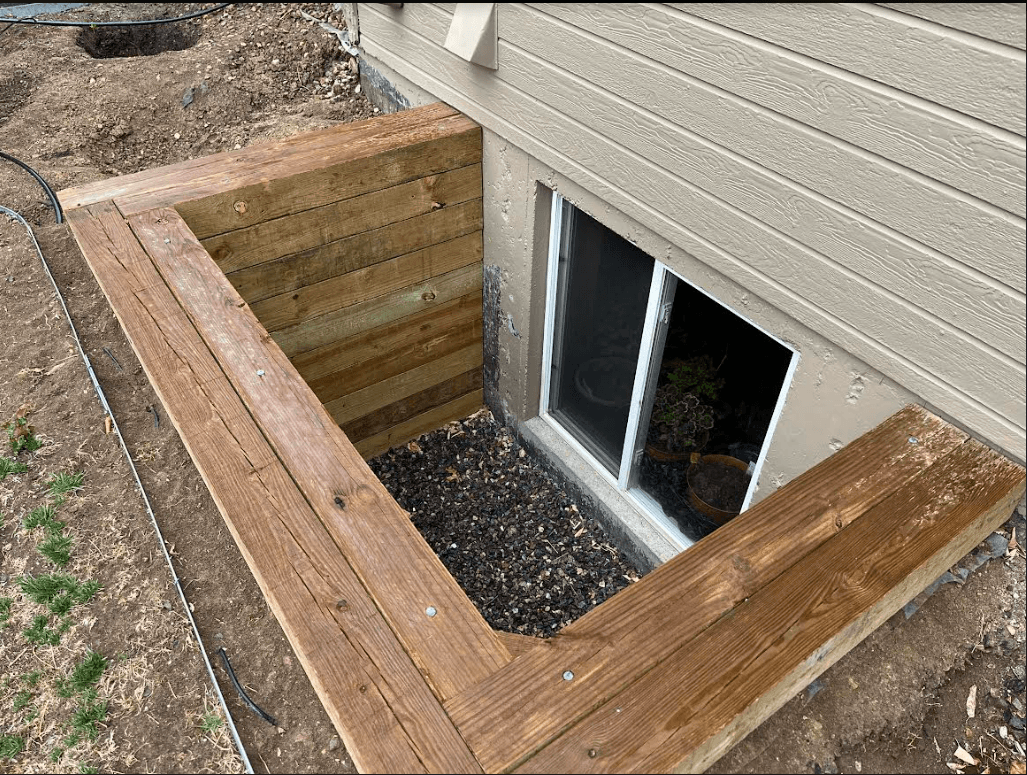A newly installed egress window well with a timber surround